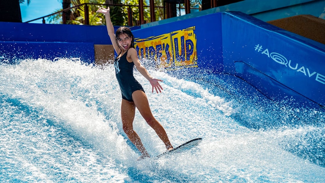 Person surfing on artificial wave at Columbia Pictures Aquaverse Pattaya.