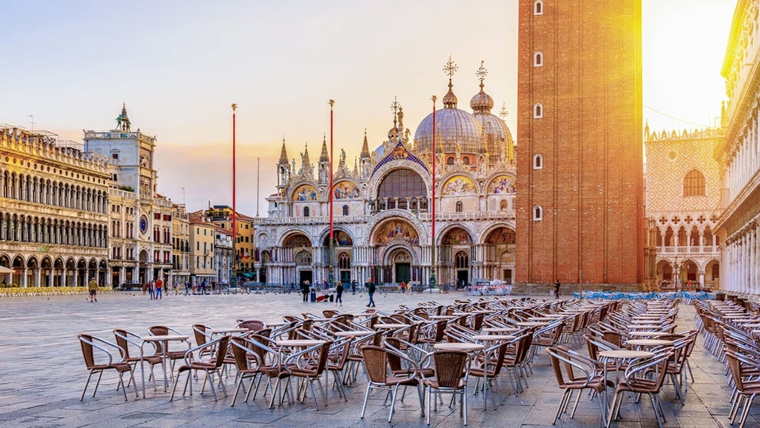 St. Mark's Basilica and Campanile in Venice with empty outdoor seating in foreground.