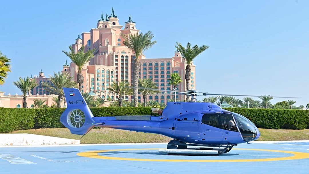Helicopter on helipad with Atlantis The Palm hotel in Dubai background.