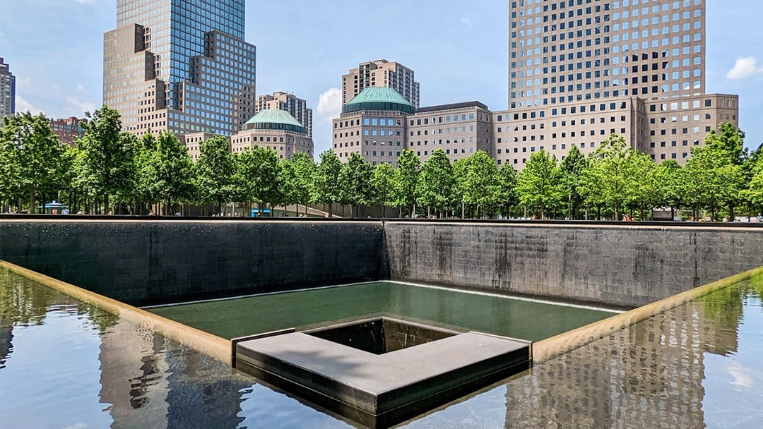 9/11 Memorial reflecting pool with surrounding skyscrapers in New York City.