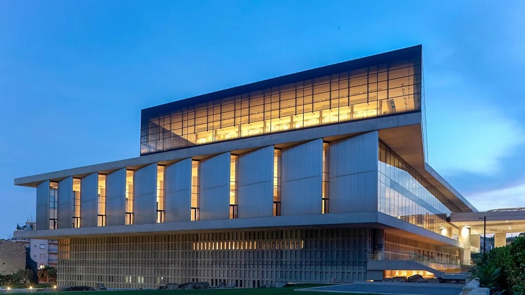 Acropolis Museum exterior illuminated during evening in Athens, Greece.