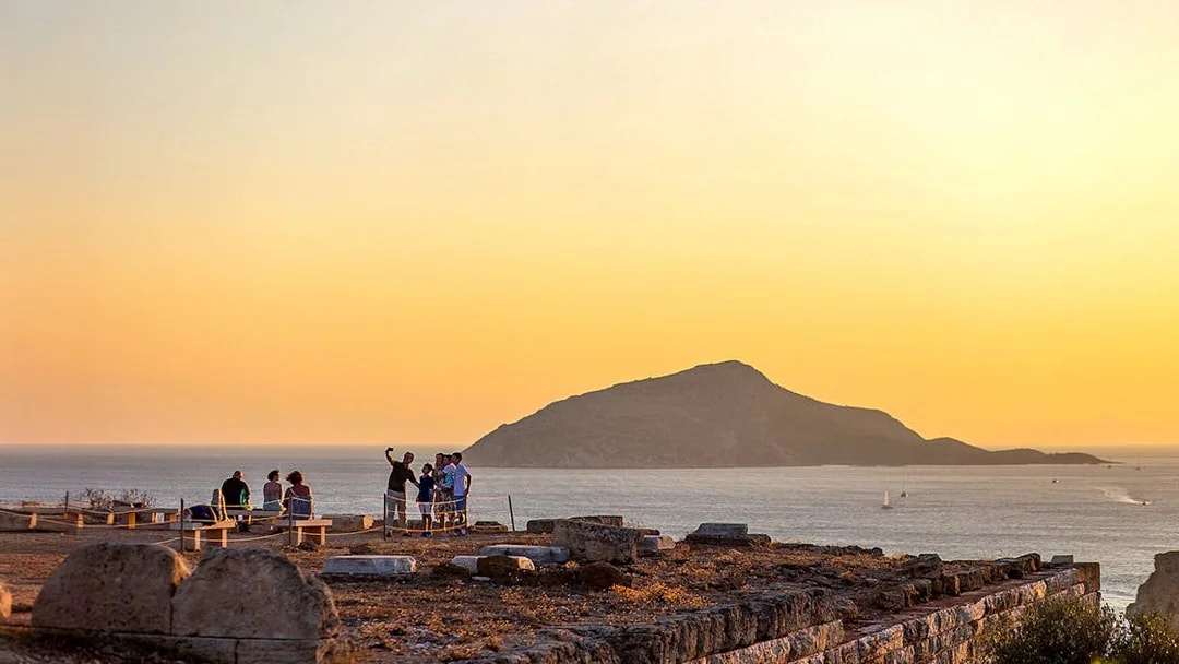Tourists taking selfie at sunset in Archaeological Site of Sounion, Greece.
