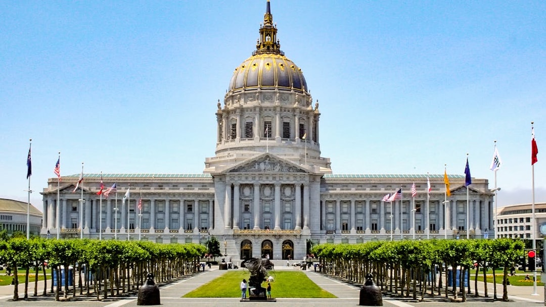 San Francisco City Hall with flags and trees in Civic Center, California.