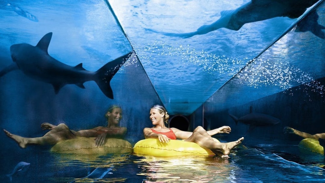 Tourist on a yellow float in a shark tunnel at Aquaventure Waterpark, Dubai.