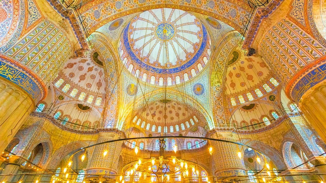 Interior of the Blue Mosque in Istanbul, showcasing intricate domed ceiling and ornate designs.