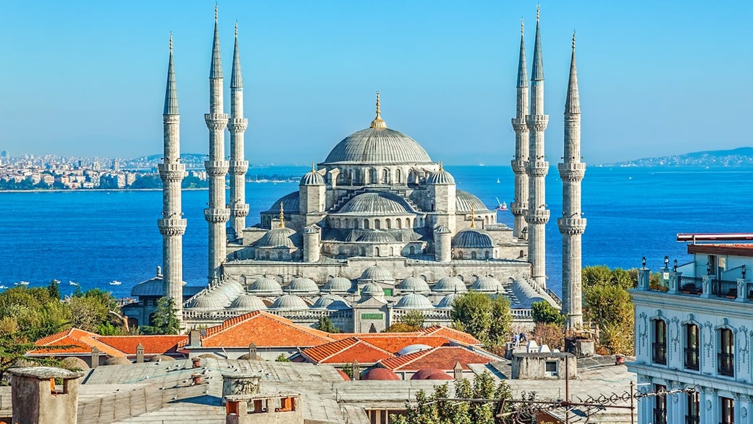 Blue Mosque exterior with minarets and domes, Istanbul skyline in background.