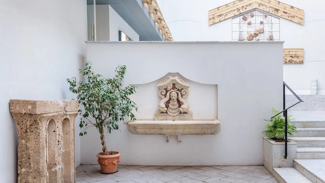 Courtyard with stone fountain and potted plants at Antonino Salinas Archaeological Museum.