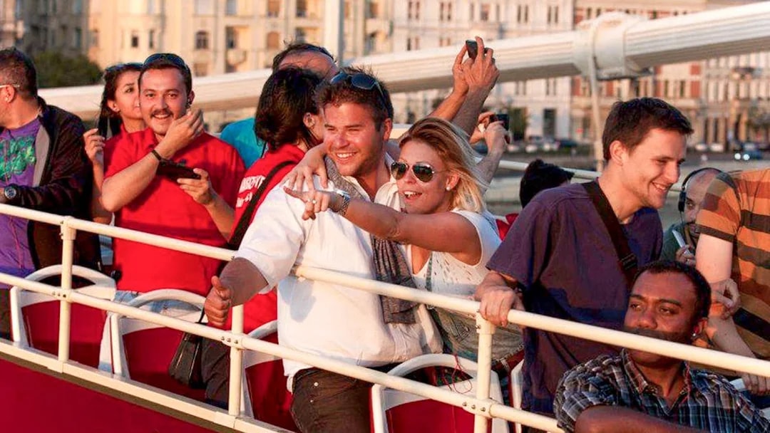 Tourists enjoying Budapest Big Bus tour near Hungarian Parliament and Danube River.