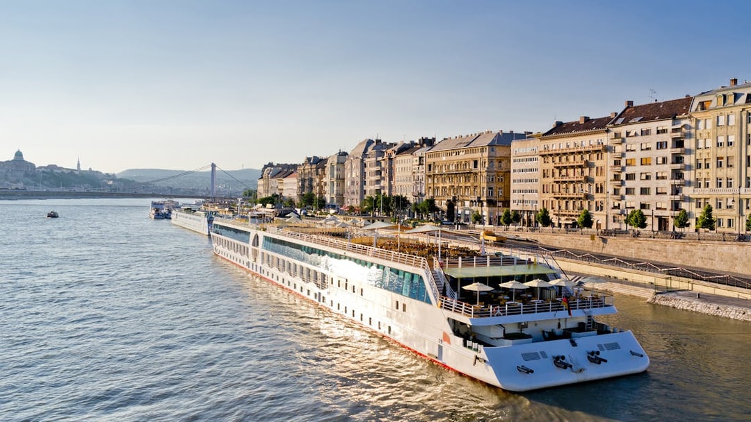 Cruise ship on Danube River with Budapest cityscape, part of 24 Hour Budapest Big Bus HOHO tour.