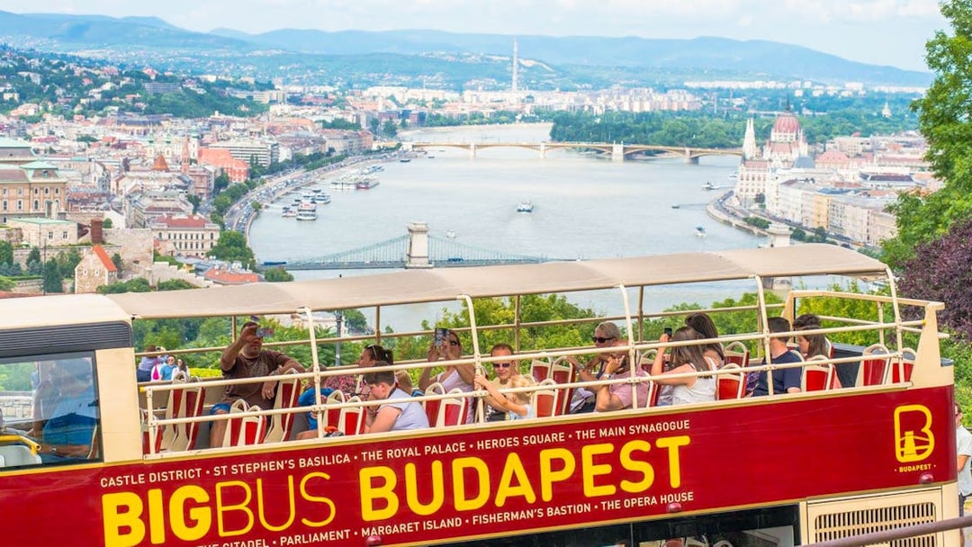 Open-top bus tour in Budapest with view of the Danube River and city landmarks.