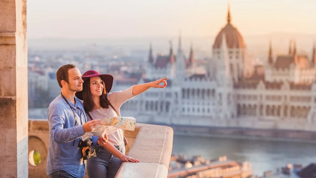 Couple with map enjoying view of Budapest Parliament building.