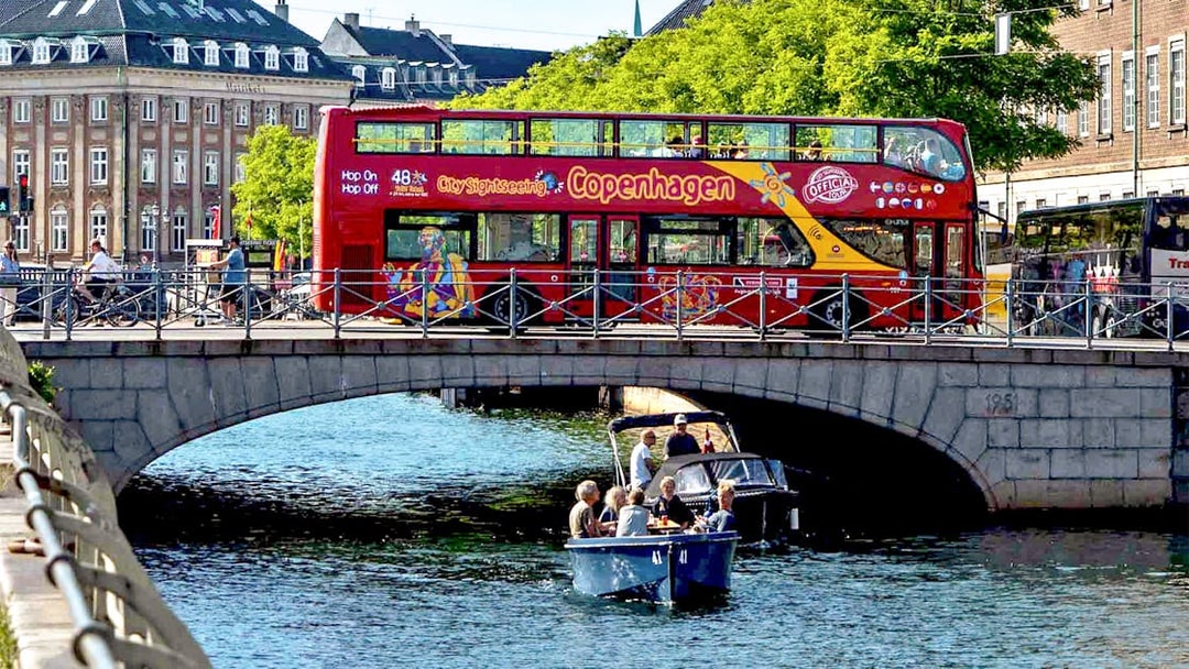 Copenhagen hop-on hop-off bus on bridge with canal cruise below.