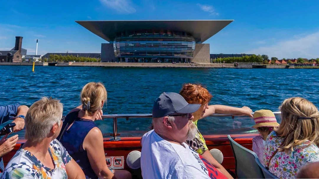 Tourists on a boat viewing the Copenhagen Opera House during a canal tour.