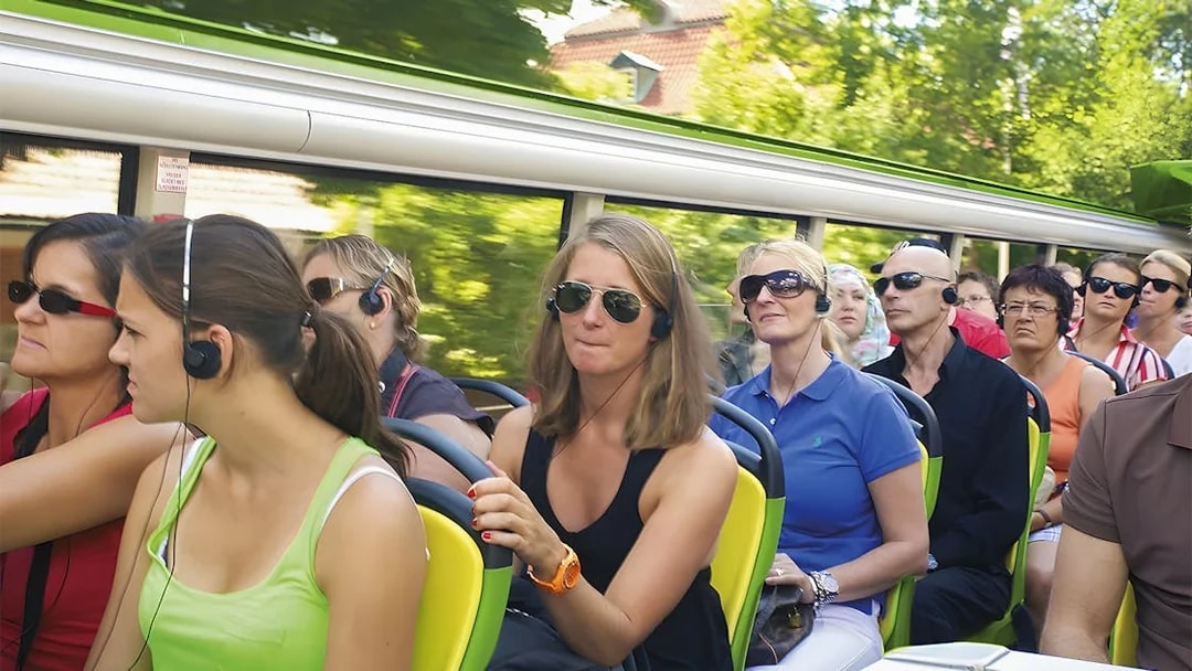 Passengers on a hop-on hop-off tour bus in Copenhagen wearing audio guides.