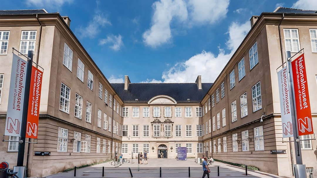 Exterior view of the National Museum of Denmark with entrance and banners.
