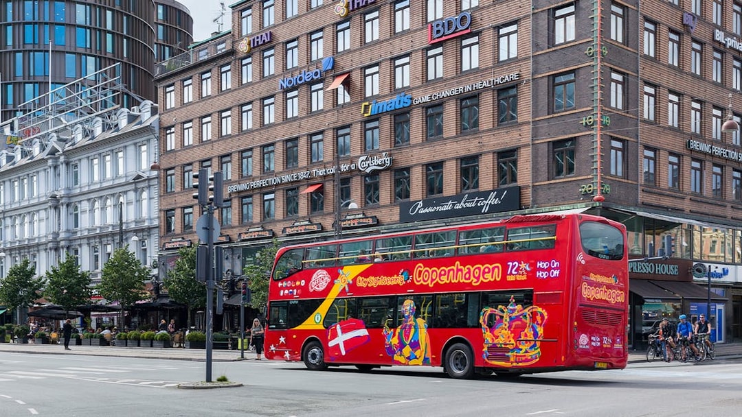 Copenhagen hop-on-hop-off tour bus passing by city buildings.