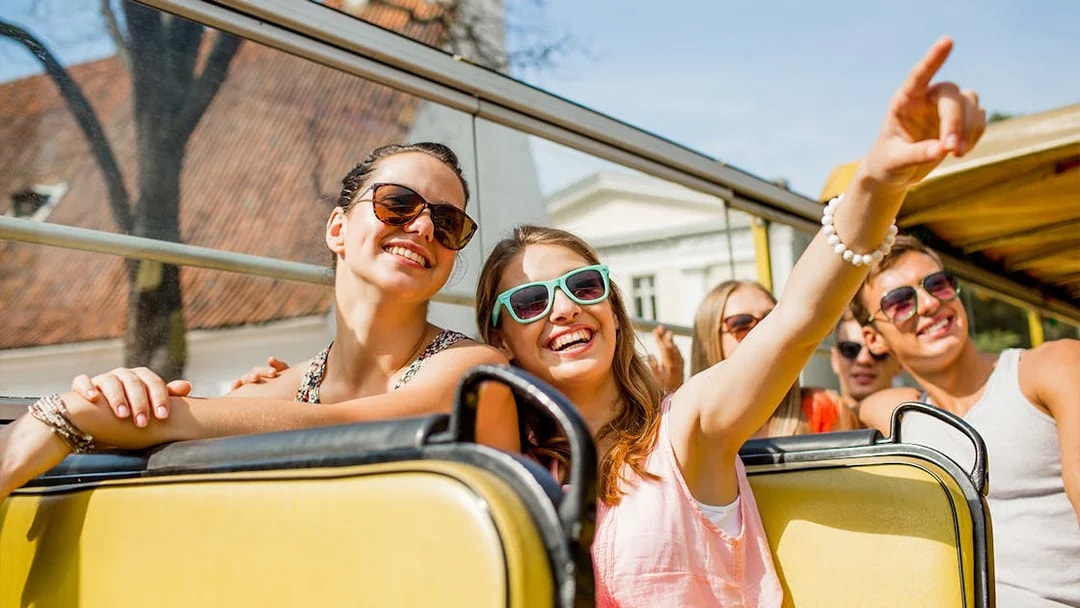 Tourists enjoying a Darwin bus tour, smiling and pointing at sights.
