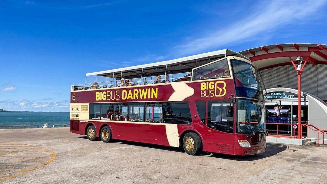 Darwin double-decker tour bus parked near waterfront and tourist facility.