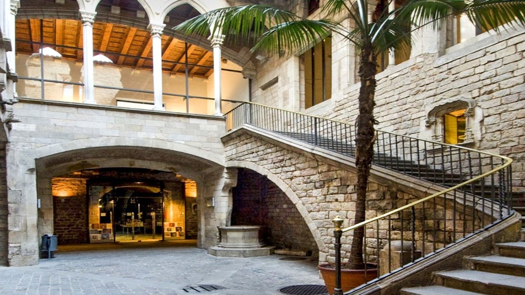 Exterior courtyard of Picasso Museum, Barcelona, featuring stone arches and a staircase.
