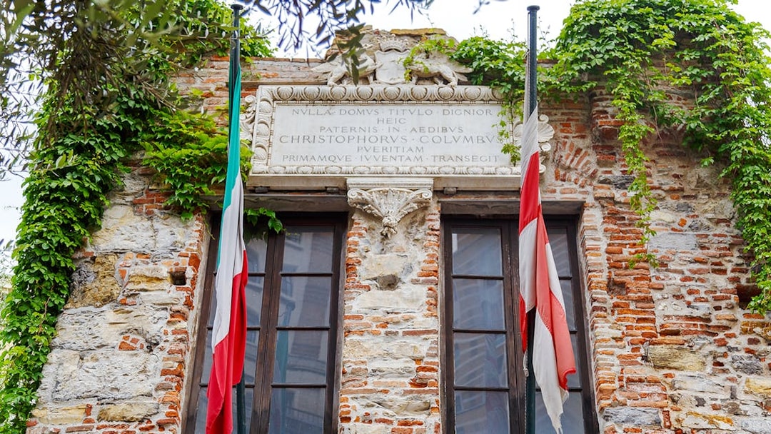 Christopher Columbus' House facade with Italian flags and ivy-covered brickwork.