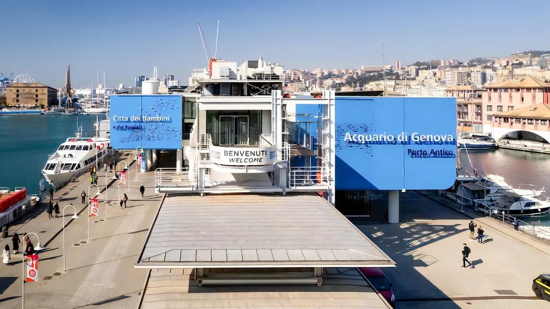Exterior view of Aquarium of Genoa and City of Kids entrance, with nearby harbor and cityscape.