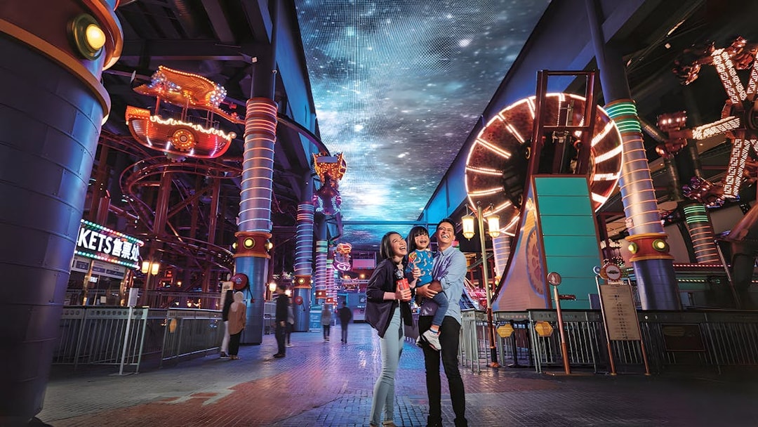 Family enjoying Genting Skytropolis Indoor Theme Park with vibrant lights and attractions.