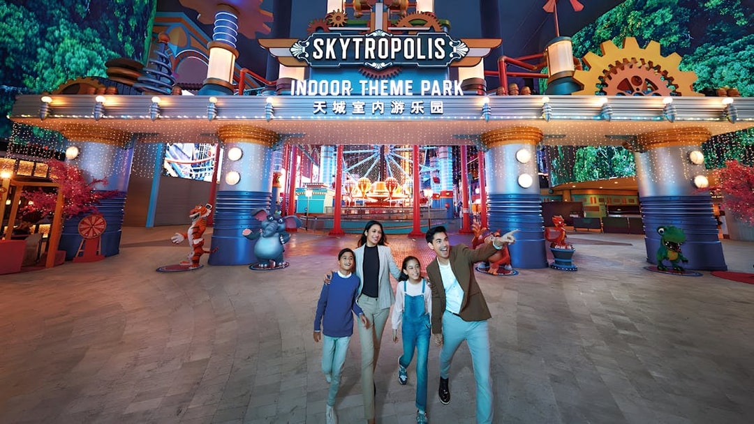Family enjoying Genting Skytropolis Indoor Theme Park entrance with colorful lights.