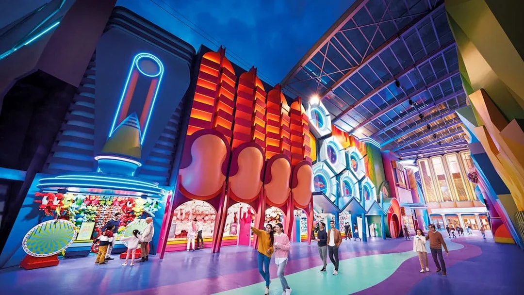 Visitors exploring vibrant neon-lit attractions at Genting SkyWorld Outdoor Theme Park.