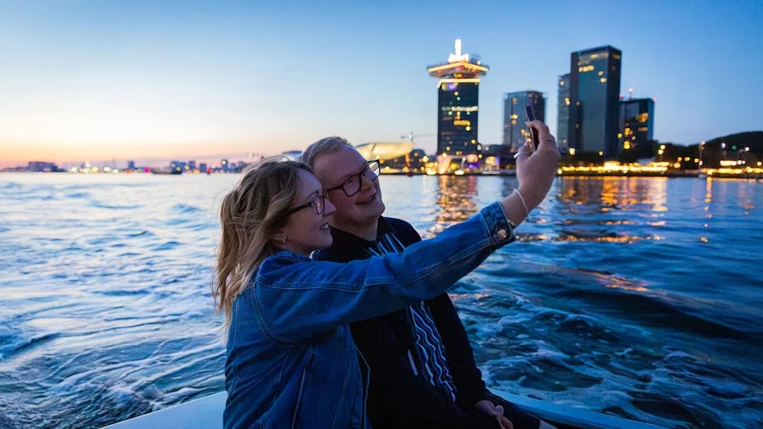 Couple taking a selfie on the Happy Valentine Evening Cruise with city skyline in the background.