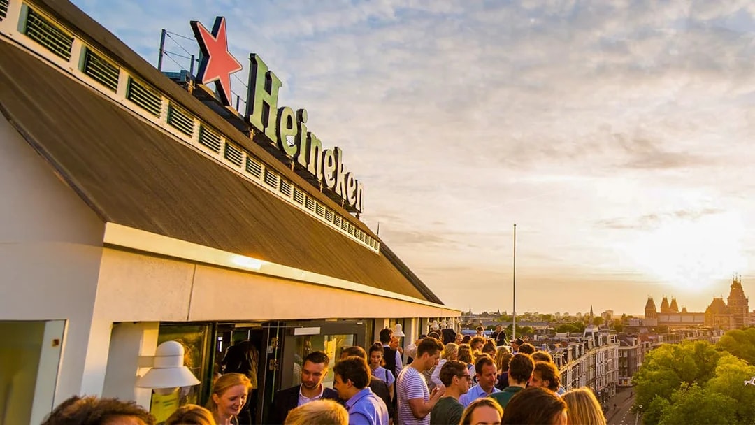 Crowd enjoying sunset at Heineken Experience rooftop in Amsterdam.