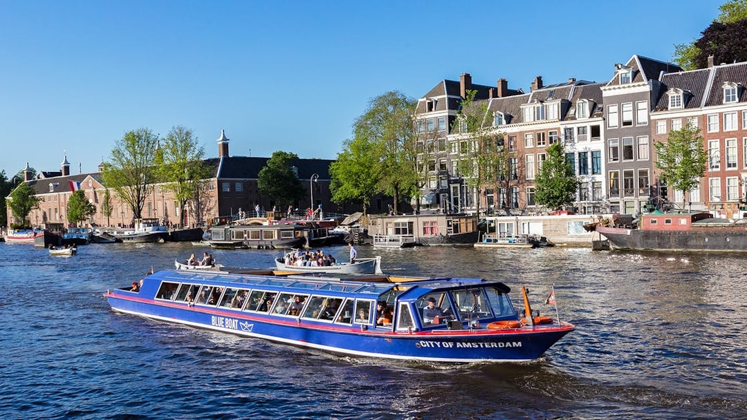 Amsterdam canal cruise boat passing historic buildings near Rembrandt House Museum.