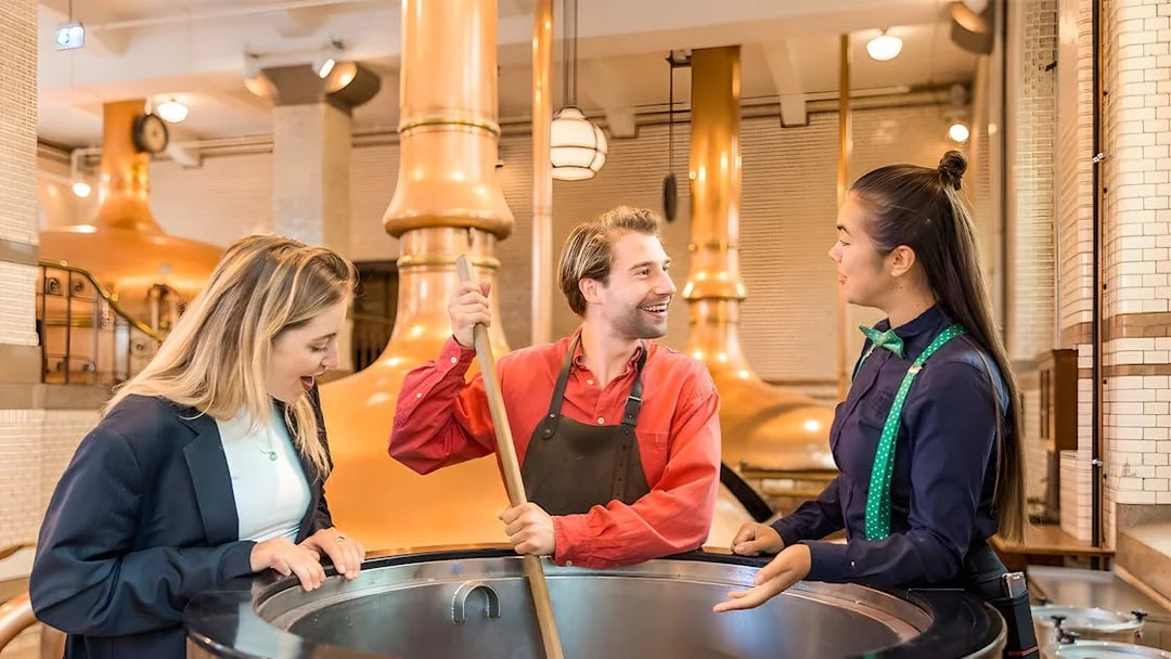 Tourists brewing beer at Heineken Experience in Amsterdam brewery.