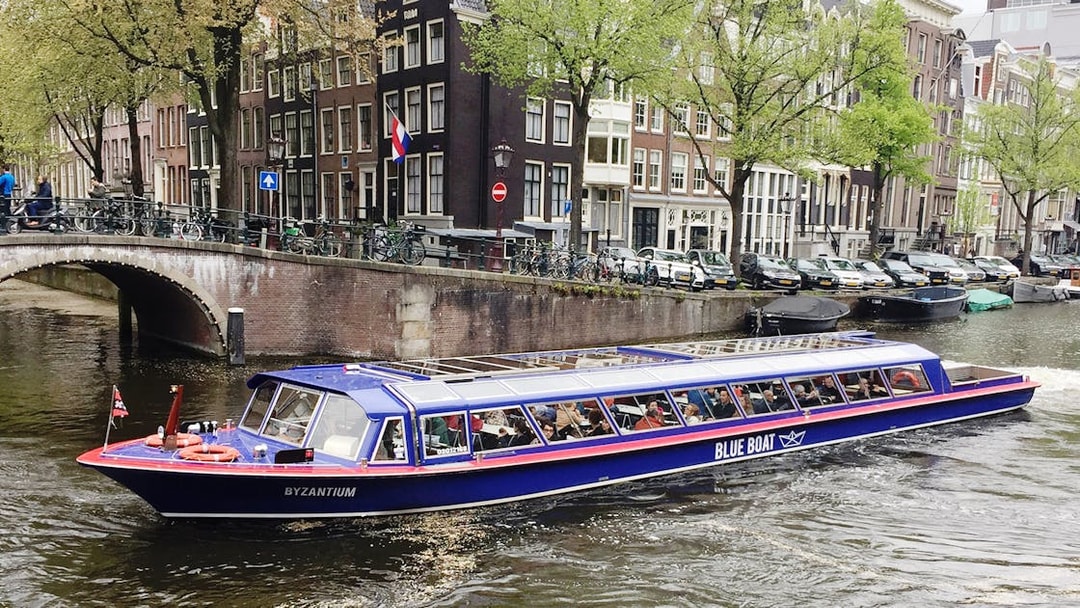 Amsterdam canal cruise boat passing historic buildings near Rembrandt House Museum.