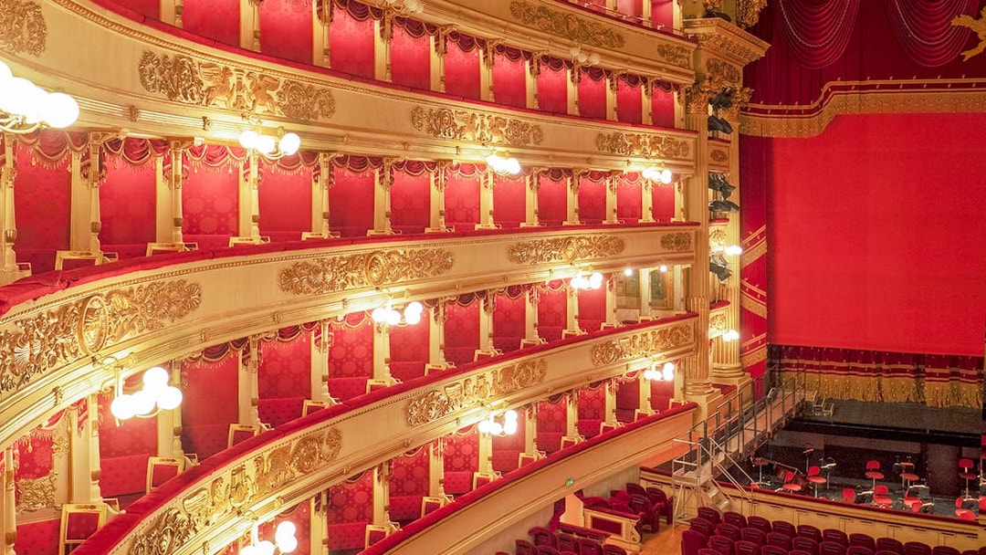 Balconies and stage of La Scala Theatre, Milan, with ornate gold detailing and red velvet seating.