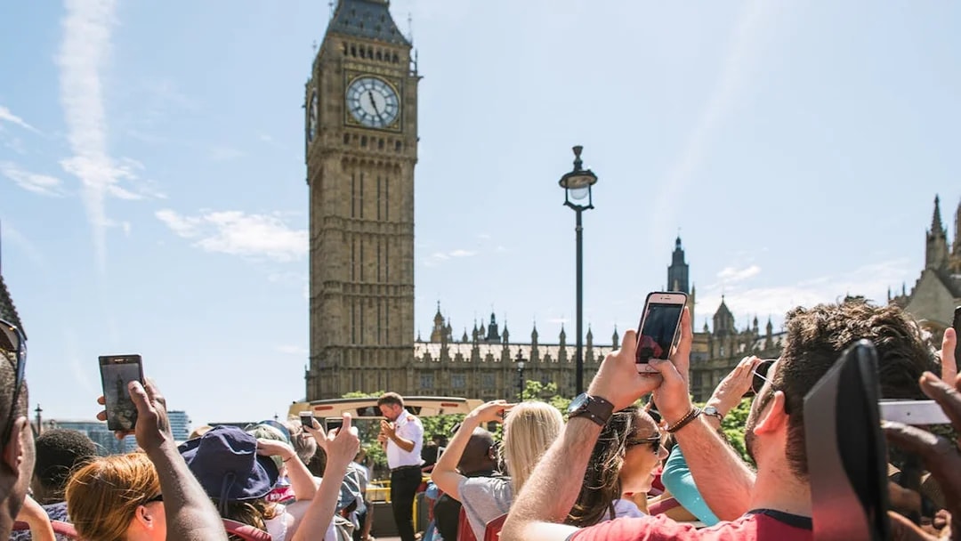 Tourists on HOHO bus taking photos of Big Ben, London.