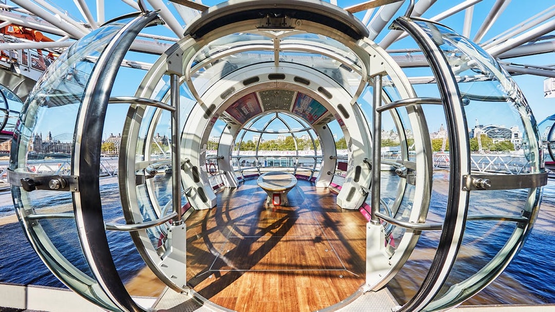 Interior view of a London Eye pod with cityscape in the background.