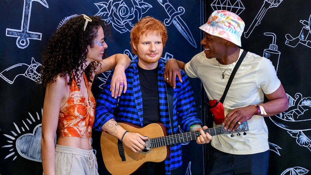 Wax figure of a celebrity with guitar at Madame Tussauds London, surrounded by visitors.