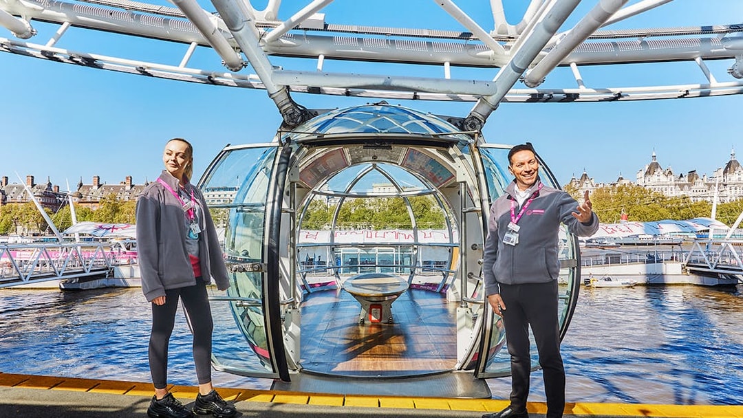 London Eye capsule with two guides welcoming visitors.