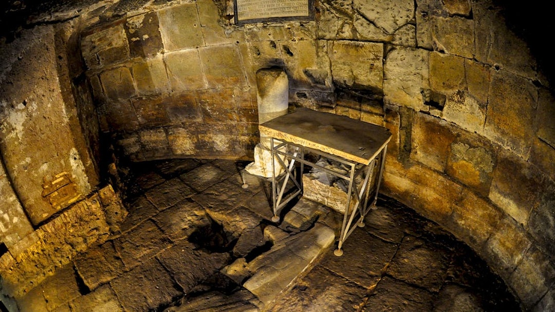 Mamertine Prison interior with ancient stone walls and table in Rome.