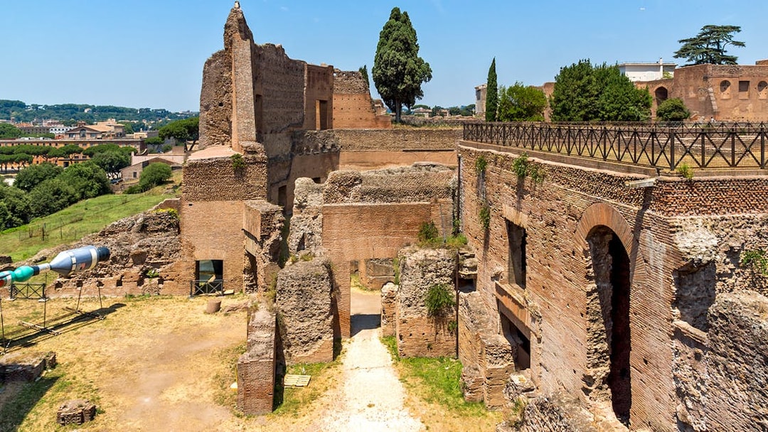 Roman Forum ruins with ancient brick structures and Palatine Hill in Rome.
