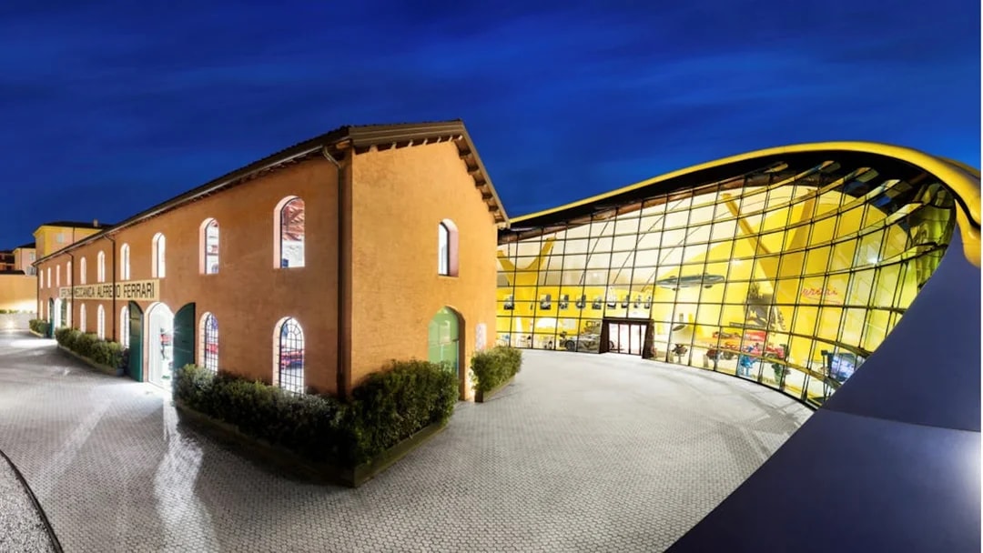 Maranello Ferrari Museum and Modena Enzo Ferrari Museum exterior at night.