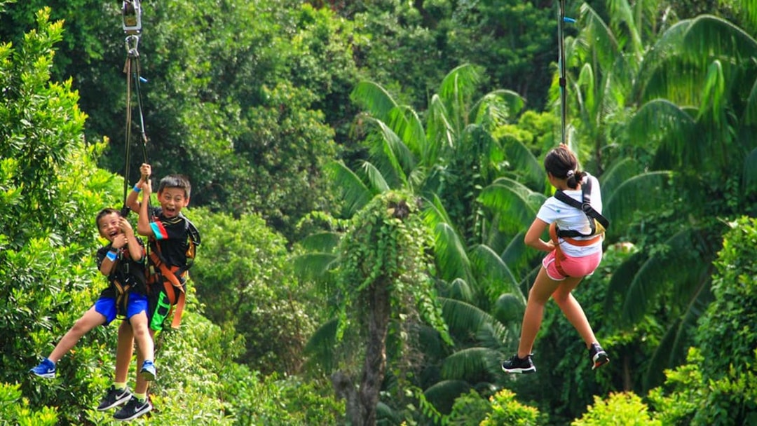 Children ziplining through lush greenery in Singapore.