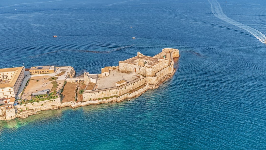 Aerial view of Maniace Castle surrounded by the sea in Syracuse, Italy.