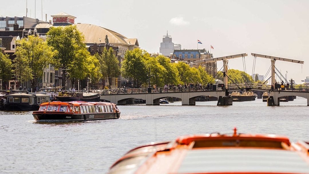 Amsterdam canal cruise boat near Magere Brug with cityscape in background.