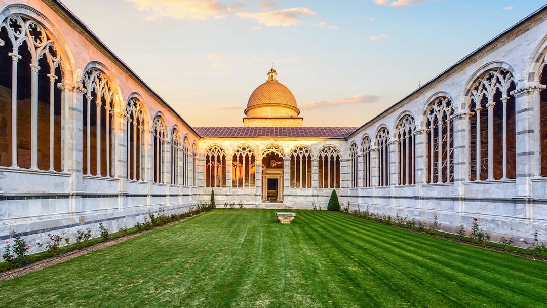Pisa Monumental Complex courtyard with arches and dome at sunset, Italy.