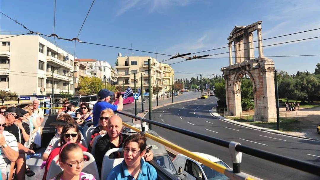 Double-decker bus tour in Athens passing Hadrian's Arch.