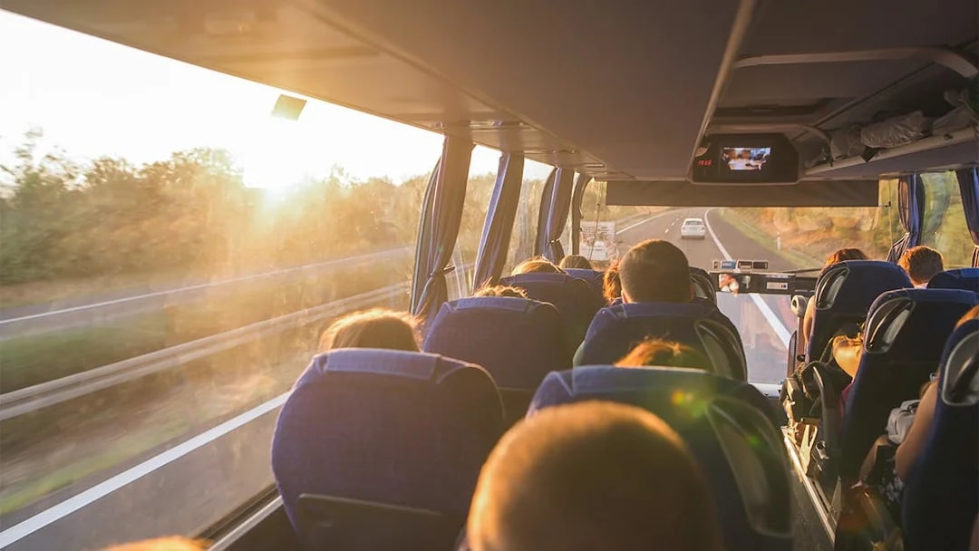 Passengers on a bus enjoying a scenic highway view at sunset, National Tickets Express.