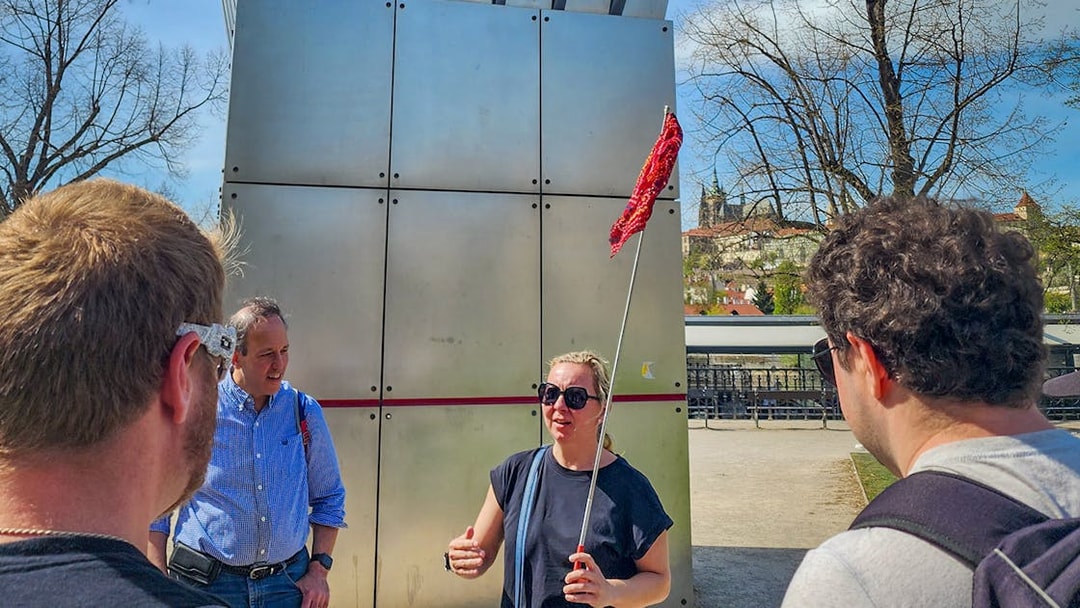 Tour guide leading a group near Prague Castle with city view in background.