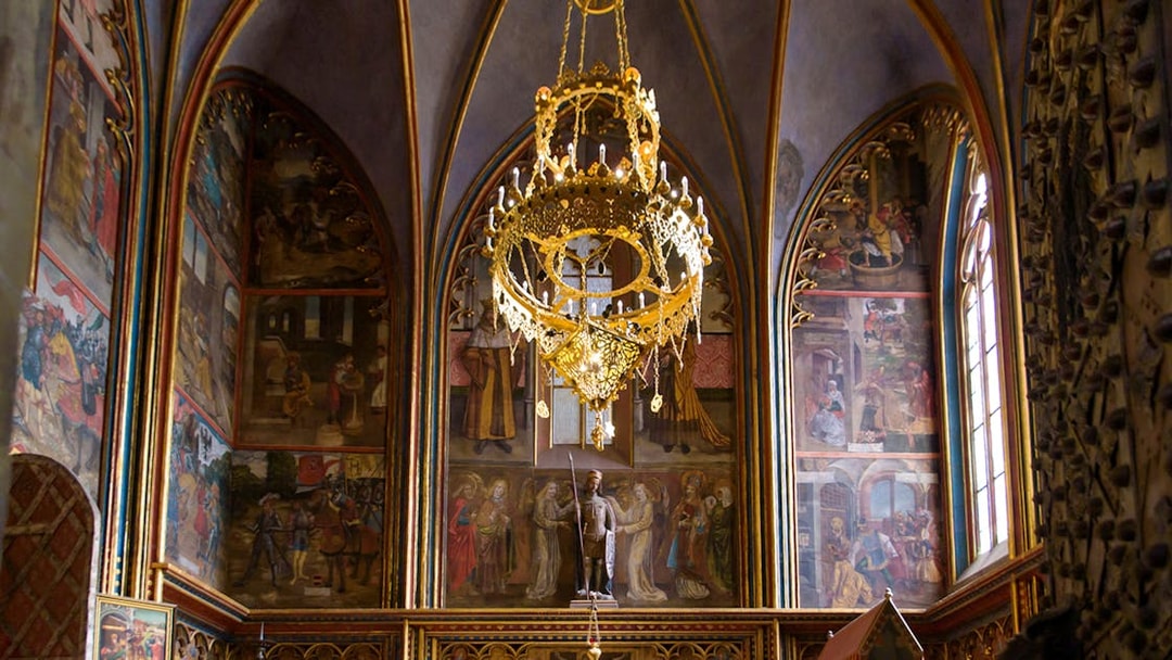 Prague Castle interior with ornate chandelier and detailed wall frescoes.