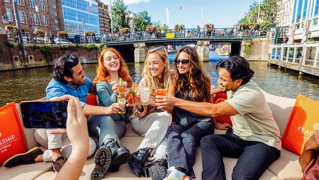 Tourists enjoying drinks on a canal cruise in Amsterdam.